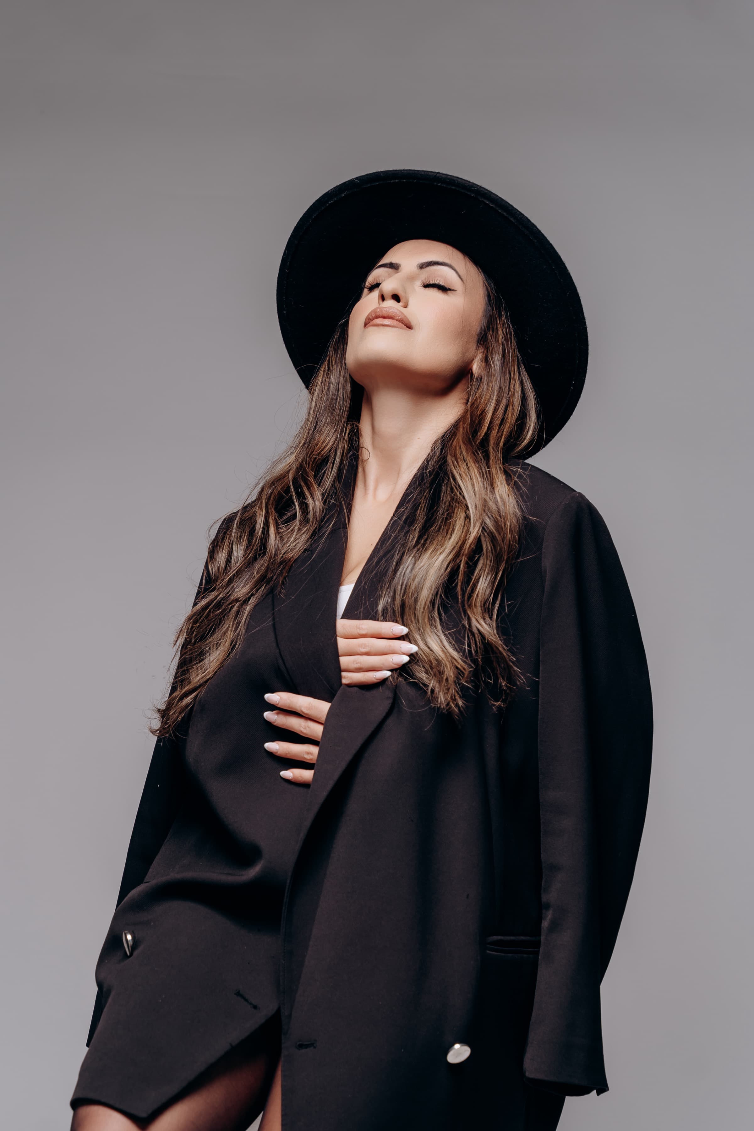 Hevi Serdar in a black hat and blazer, studio portrait