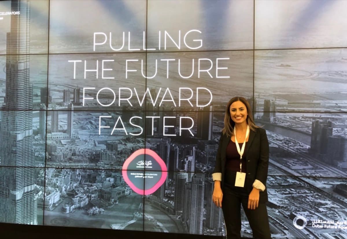 Hevi Serdar on stage beside a Pulling the Future Forward Faster screen