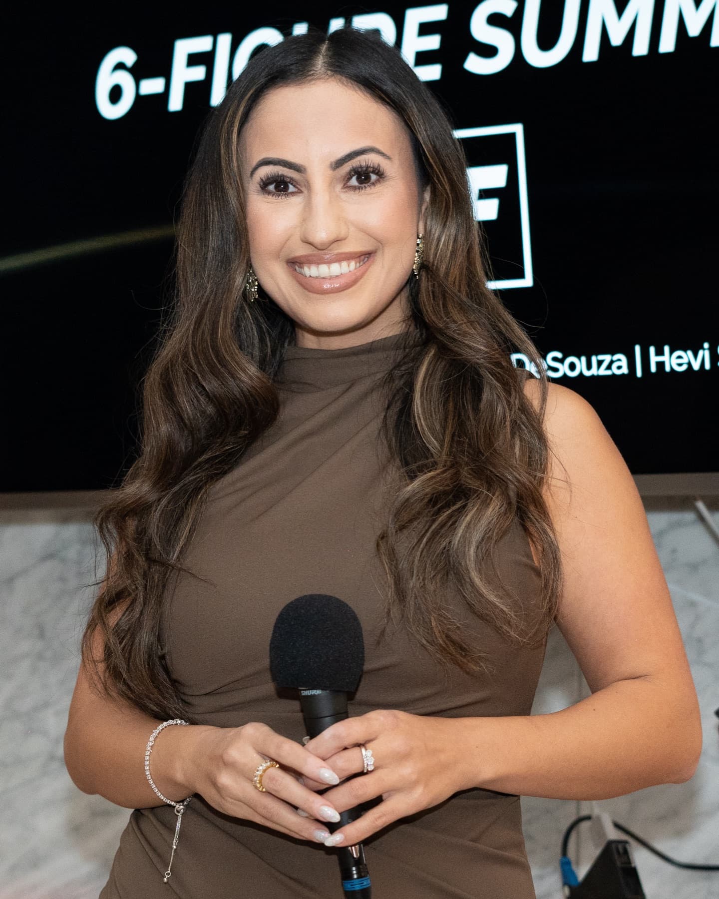 Hevi Serdar holding a microphone at the 6-Figure Summit