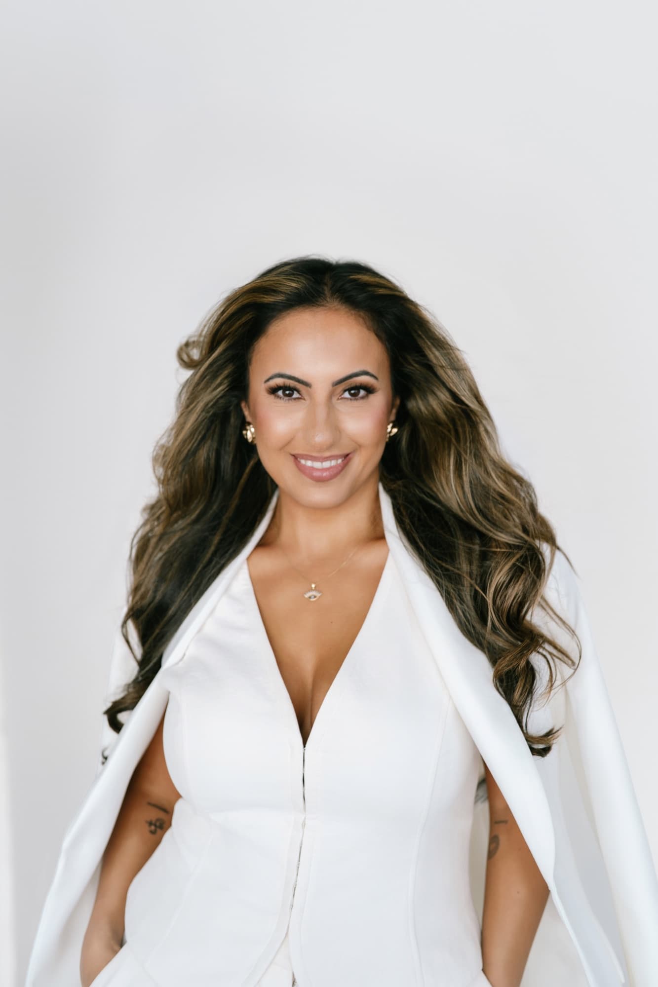 Hevi Serdar in a white cape dress, smiling