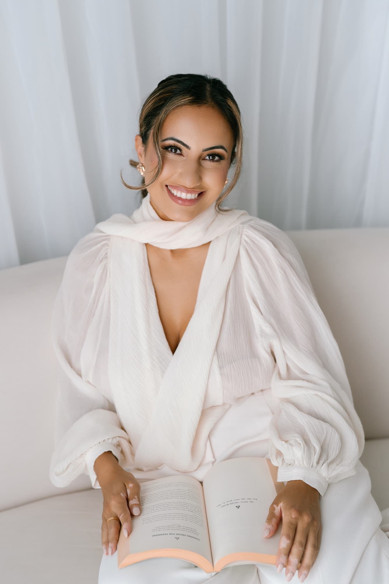 Hevi Serdar in white, smiling over an open book