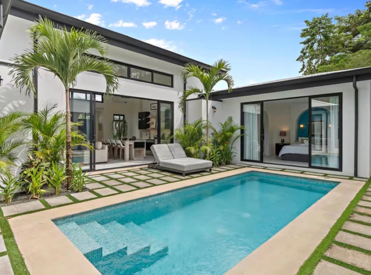 A villa pool framed by palms under a clear sky